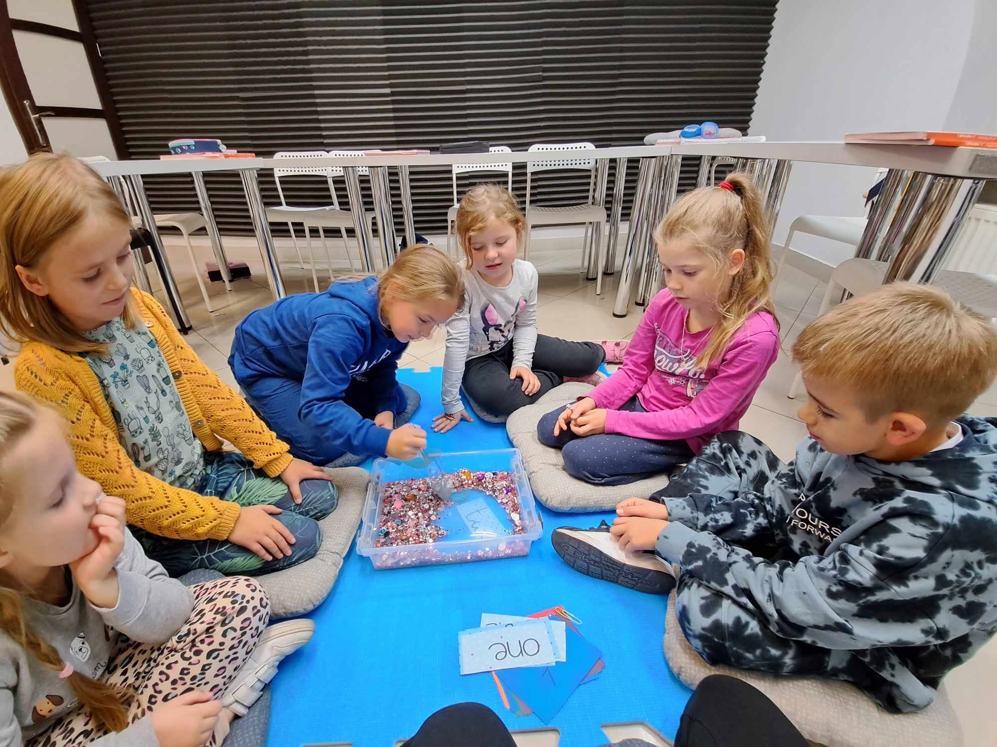 Dzieci uczące się angielskiego przez zabawę na dywanie